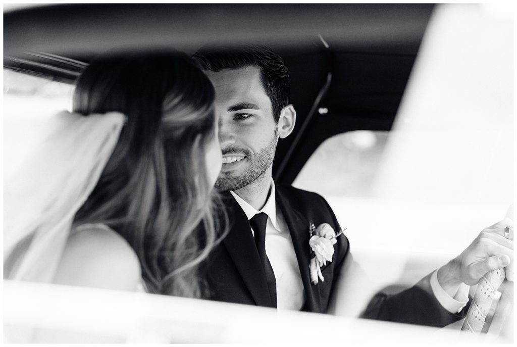 Groom looks over at bride in their get away car after their wedding reception in detroit michigan.
