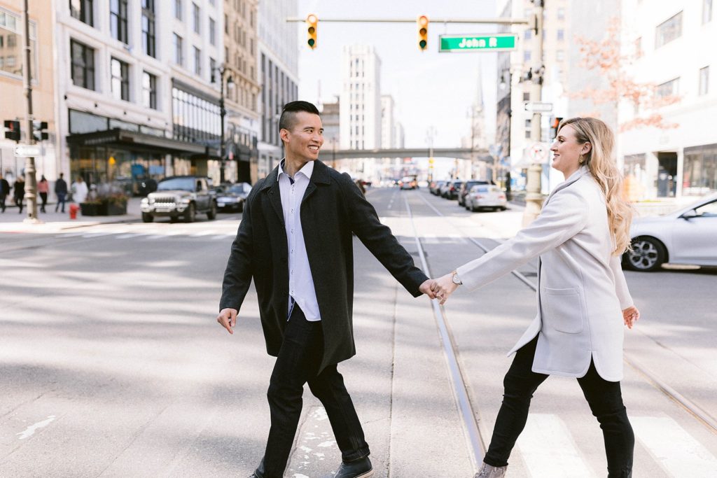 engaged couple walks across road downtown detroit
