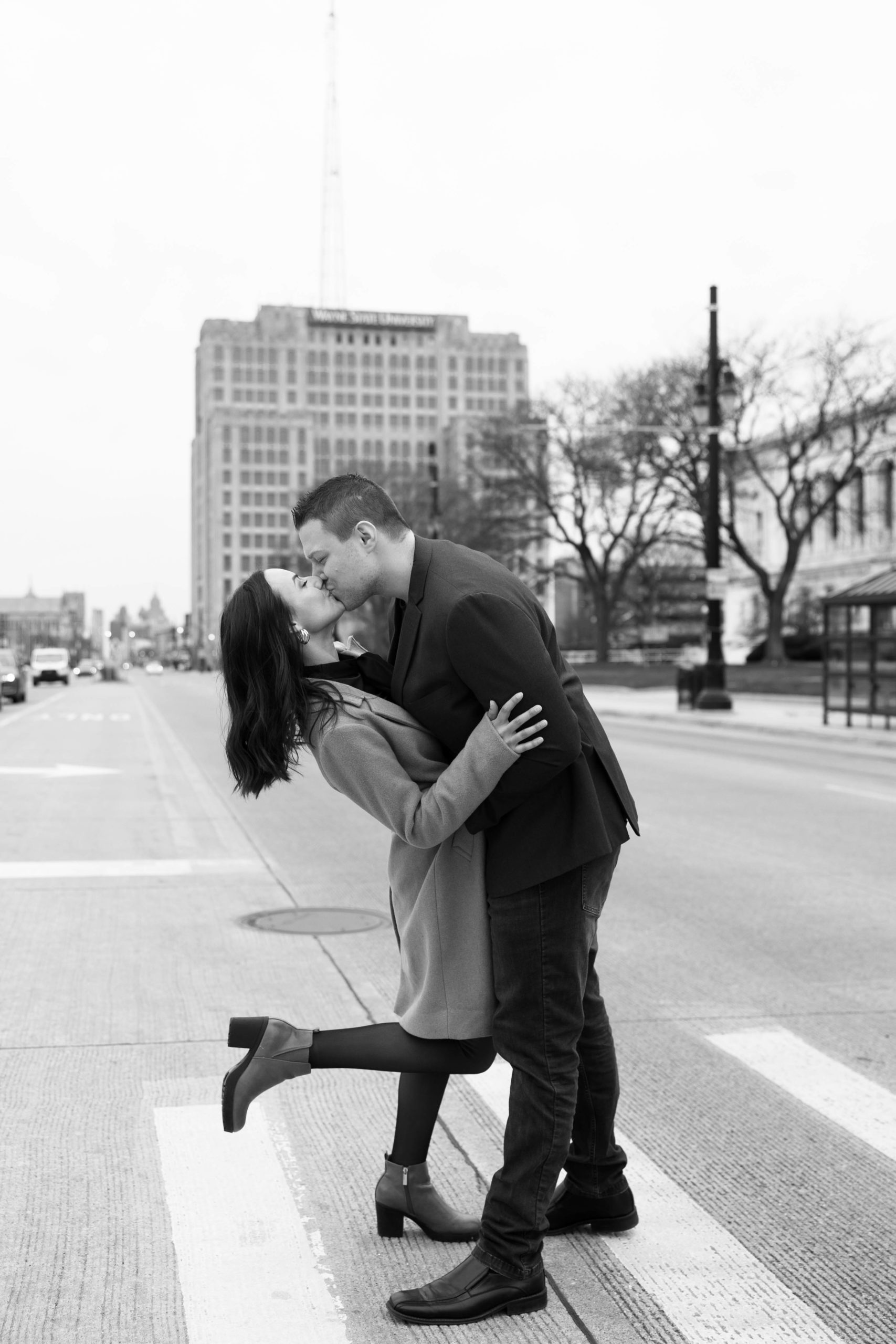man and woman who appear to be engaged kiss in the street