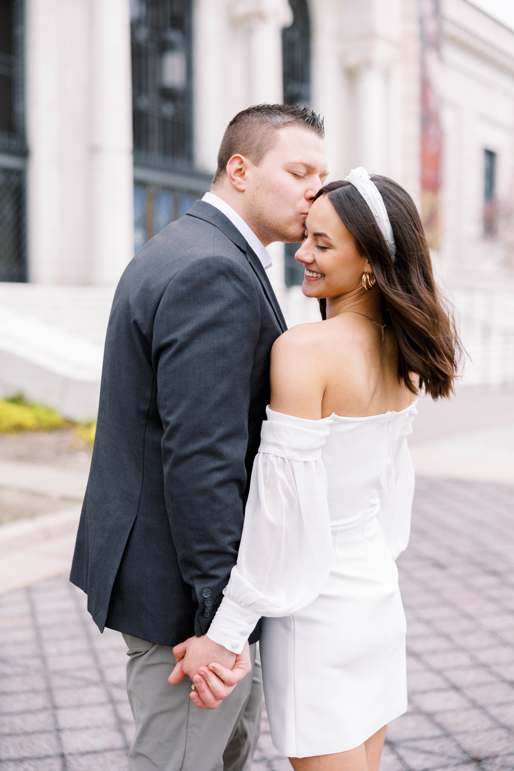 man kisses woman in a white dress